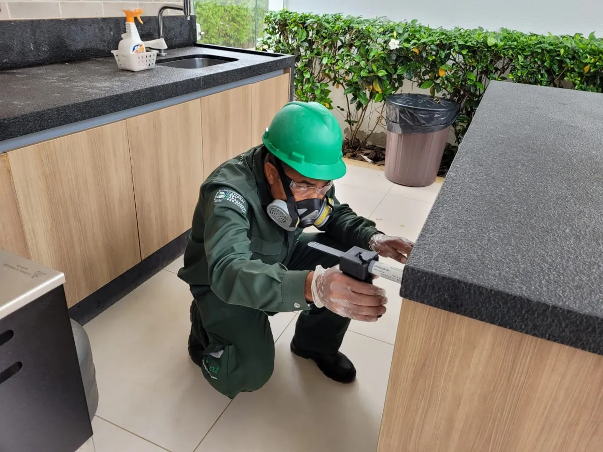 Técnico da Detecta aplicando gel inseticida na cozinha de uma residência
