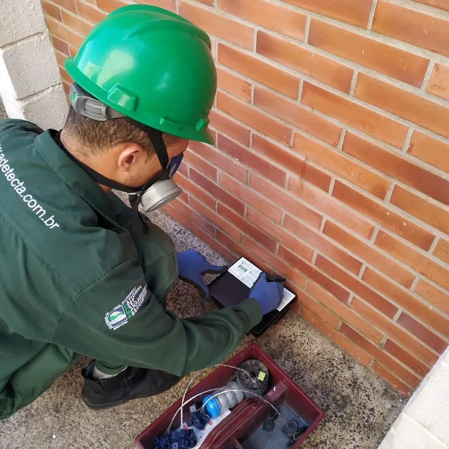 Técnico da Detecta inspecionando estação de monitoramento junto a uma parede